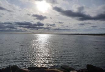 Matin ensoleillé vu depuis «Seaside Bliss in albaek» au Danemark, reflets sur la mer et rochers au premier plan.