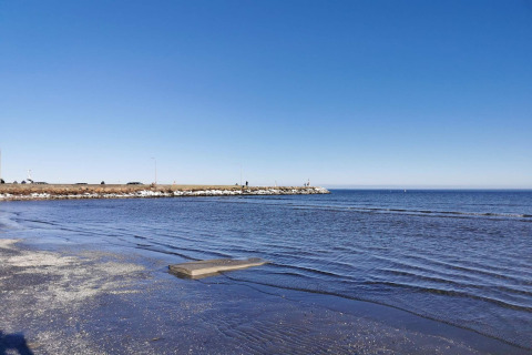 Udsigt over havet fra stranden ved Seaside Bliss i Albæk, Danmark, med en klar blå himmel.