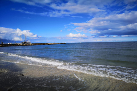 Vue du littoral à Seaside Bliss à Albaek, Danemark, avec mer calme, yachts et ciel partiellement nuageux.