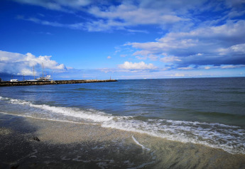 Vue du littoral à Seaside Bliss à Albaek, Danemark, avec mer calme, yachts et ciel partiellement nuageux.