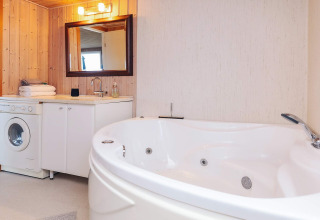 Moderne badkamer in Seaside Bliss in Albaek, Denemarken, met jacuzzi, wasmachine en houten muren.