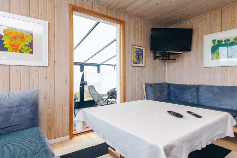 Stue i Seaside Bliss i Albaek, Danmark med træpaneler, moderne kunst, fladskærm og blå sofaer.