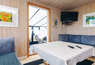 Sala de estar en Seaside Bliss en Albaek, Dinamarca con paredes de madera, arte y sofá azul.