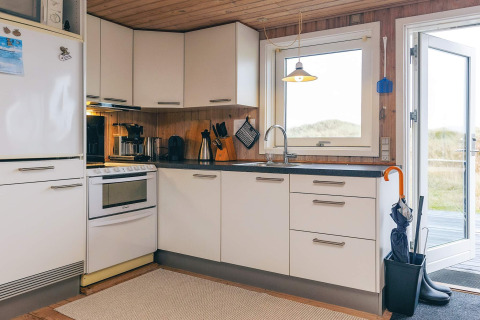 Cucina moderna al Seaside Bliss lodge ad Albaek, Danimarca, con armadi bianchi e luce naturale.