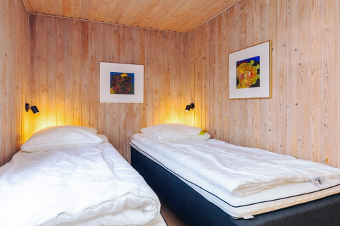 Deux lits simples avec du linge blanc dans une chambre en bois, Seaside Bliss à Albaek, Danemark.