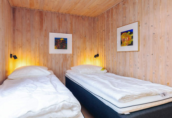 To enkeltsenge med hvidt sengetøj i et træbeklædt værelse på Seaside Bliss i Albaek, Danmark.