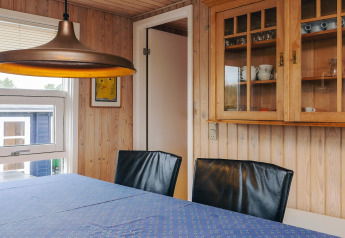 Spiseområde i Seaside Bliss i Albaek, Danmark, med trævægge, glasvitrine og moderne lamper.