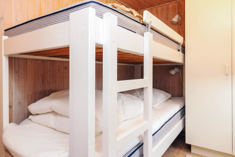 Værelse med køjesenge og hvid garderobe på Seaside Bliss i Albaek, Danmark, med træbeklædte vægge.