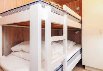 Habitación con literas y armario blanco en Seaside Bliss en Albaek, Dinamarca, con paredes de madera.