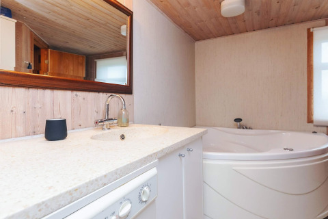 Badezimmer in der Lodge Seaside Bliss in Albaek, Dänemark, mit Eckbadewanne und großem Spiegel.