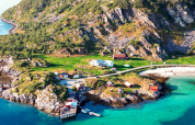 Luchtfoto van Engvik Hytta, met kusthuisjes, turquoise water, strand en groene heuvels in Zweden.