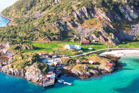 Vista aerea di Engvik Hytta, cabine sul mare, acque turchesi, spiaggia e colline verdi nella natura svedese.