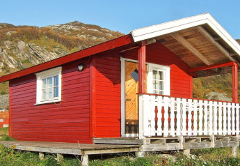 Rood houten huisje genaamd ENGVIK HYTTA 83699 met een witte veranda, gelegen in een heuvelachtig landschap.