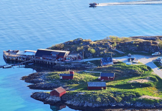 Vista costiera da Engvik Hytta 83699 in Svezia con casette rosse, molo e una barca sull’acqua tranquilla.