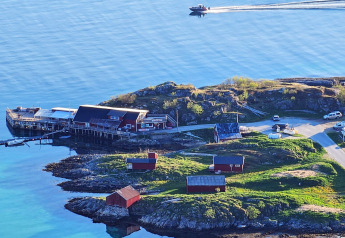Vista costera desde Engvik Hytta 83699 en Suecia, con cabañas rojas, muelle y bote sobre aguas tranquilas.