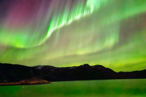 L'aurora boreale splende su montagne e lago vicino alla baita ENGVIK HYTTA 83699 in Svezia.