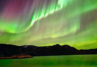 L'aurora boreale splende su montagne e lago vicino alla baita ENGVIK HYTTA 83699 in Svezia.