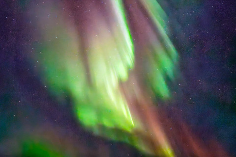 Aurora boreale con sfumature verdi e viola, vista dalla cabina ENGVIK HYTTA 83699 sotto il cielo notturno svedese.