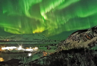 Aurora boreale sopra montagne innevate e la cabina Engvik Hytta 83699 in Svezia, fotografia notturna.