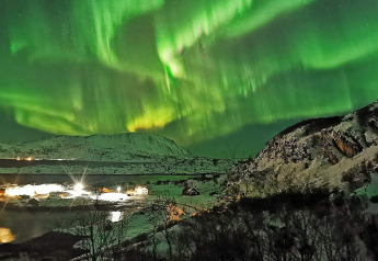 Auroras boreales brillan sobre montañas nevadas y la cabaña Engvik Hytta 83699 en Suecia por la noche.