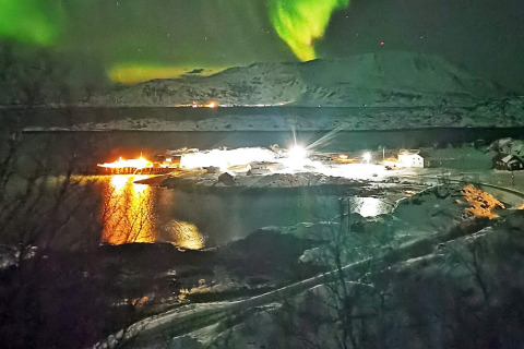 Aurora boreale sopra baita innevata presso ENGVIK HYTTA 83699 in Svezia, riflessi luminosi sull’acqua.
