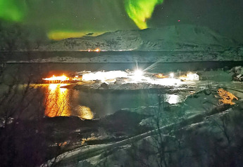 Auroras boreales sobre cabaña nevada en ENGVIK HYTTA 83699, Suecia, reflejando luces en el agua.
