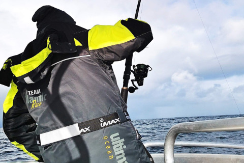 Persona con giacca 'TEAM Atlantic Race' che pesca da una barca vicino a ENGVIK HYTTA 83699 in Svezia.