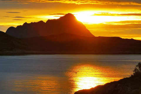 Tramonto dorato dietro il profilo montano visto da Engvik Hytta 83699 in Svezia, riflesso sul lago.