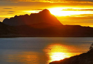Tramonto dorato dietro il profilo montano visto da Engvik Hytta 83699 in Svezia, riflesso sul lago.