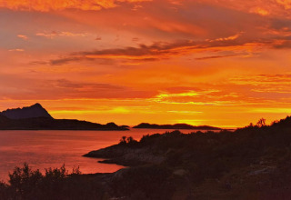 Tramonto arancione infuocato sul lago e montagne visto da Engvik Hytta 83699 in Svezia, cielo suggestivo.