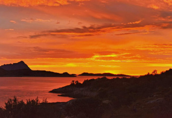 Atardecer naranja intenso sobre el lago y montañas visto desde la cabaña Engvik Hytta 83699 en Suecia.