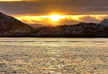Uitzicht op zonsondergang vanaf Engvik Hytta 83699, Zweden, met besneeuwde bergen en gouden meer.