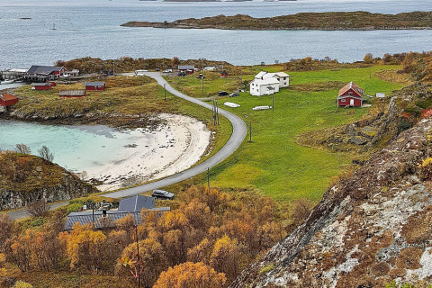 Vista da Engvik Hytta 83699 in Svezia sulla costa, case, strada curvata e alberi autunnali vicino al mare.