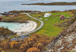 Vista da Engvik Hytta 83699 in Svezia sulla costa, case, strada curvata e alberi autunnali vicino al mare.