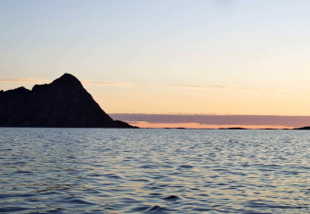 Uitzicht bij zonsondergang vanaf ENGVIK HYTTA 83699 in Zweden, kalme zee en silhouet van een eiland.