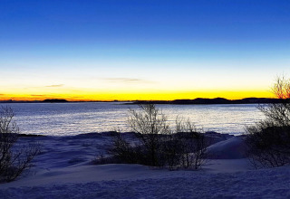 Splendido tramonto sulla riva innevata visto dalla cabina Engvik Hytta 83699 in Svezia, vicino all’acqua.