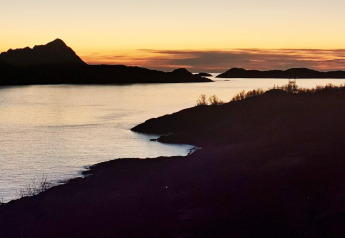 Vista al atardecer desde Engvik Hytta 83699 en Suecia, con colinas y agua serena en primer plano.