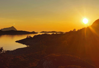 Tramonto su montagne e acqua dalla cabina Engvik Hytta 83699 in Svezia, bagliore dorato sul paesaggio.