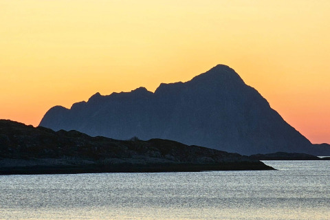 Tramonto su montagne e lago visto da ENGVIK HYTTA 83699 in Svezia, sagome scure contro cielo arancione.