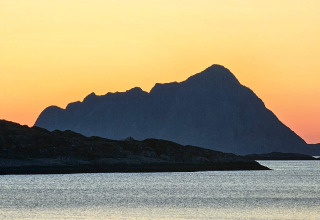Tramonto su montagne e lago visto da ENGVIK HYTTA 83699 in Svezia, sagome scure contro cielo arancione.