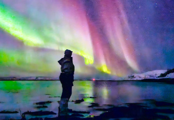 Persoon geniet van het noorderlicht bij een meer bij Engvik Hytta 83699 in Zweden onder een gekleurde lucht.