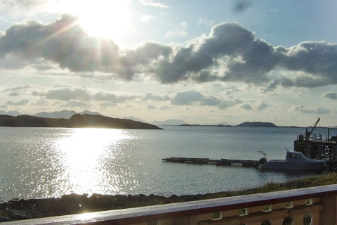 Tramonto dalla cabina ENGVIK HYTTA 83699 in Svezia, con lago, molo e colline all’orizzonte.