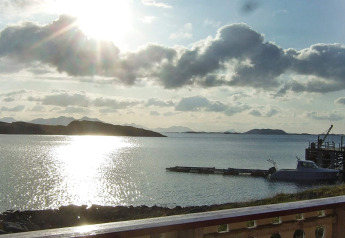 Vista al atardecer desde la cabaña ENGVIK HYTTA 83699 en Suecia, con lago, muelle y colinas al fondo.