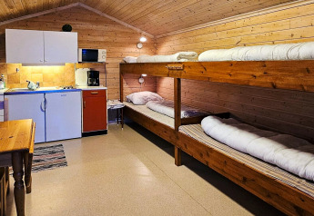 Interieur van de Engvik Hytta 83699 hut in Zweden met keuken en houten stapelbedden.