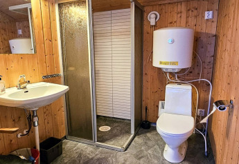 Badkamer met houten muren, douche, toilet en boiler in ENGVIK HYTTA 83699, Zweden.