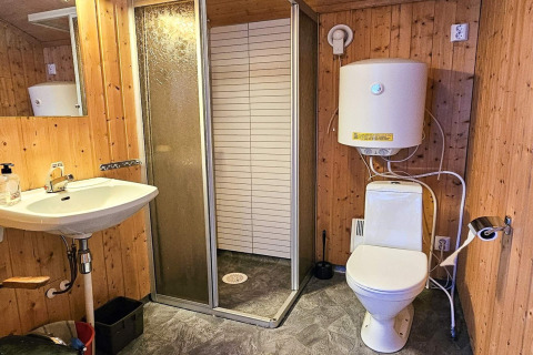 Bagno rustico con pareti in legno, doccia, WC e scaldabagno in ENGVIK HYTTA 83699, Svezia.