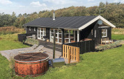 Houten vakantiehuis met terras en hottub, gelegen in groene omgeving in Øster Assels, Denemarken.