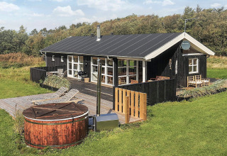 Casa de vacaciones de madera con terraza y jacuzzi, rodeada de naturaleza en Øster Assels, Dinamarca.