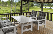 Terraza con muebles de exterior blancos y cojines sobre tarima de madera, vista a la naturaleza en Frändefors, Suecia.