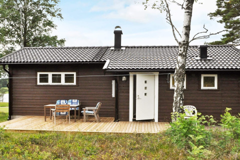Ferienhaus für 4 Personen in Frändefors, Schweden, mit Holzterrasse und Gartenmöbeln im Grünen.